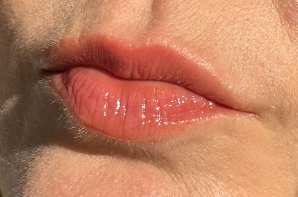 Wearing Milani Fruit Fetish Lip Oil in Cherry Lime on the lips