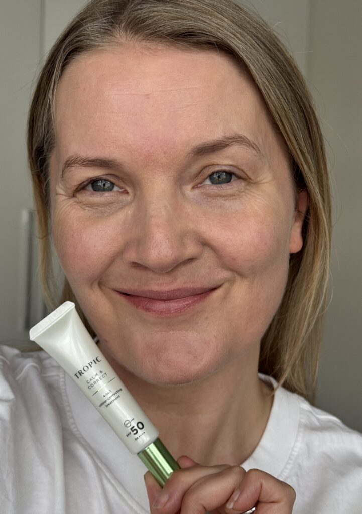Wearing Tropic Skincare Calm & Correct whilst holding the tube in hand