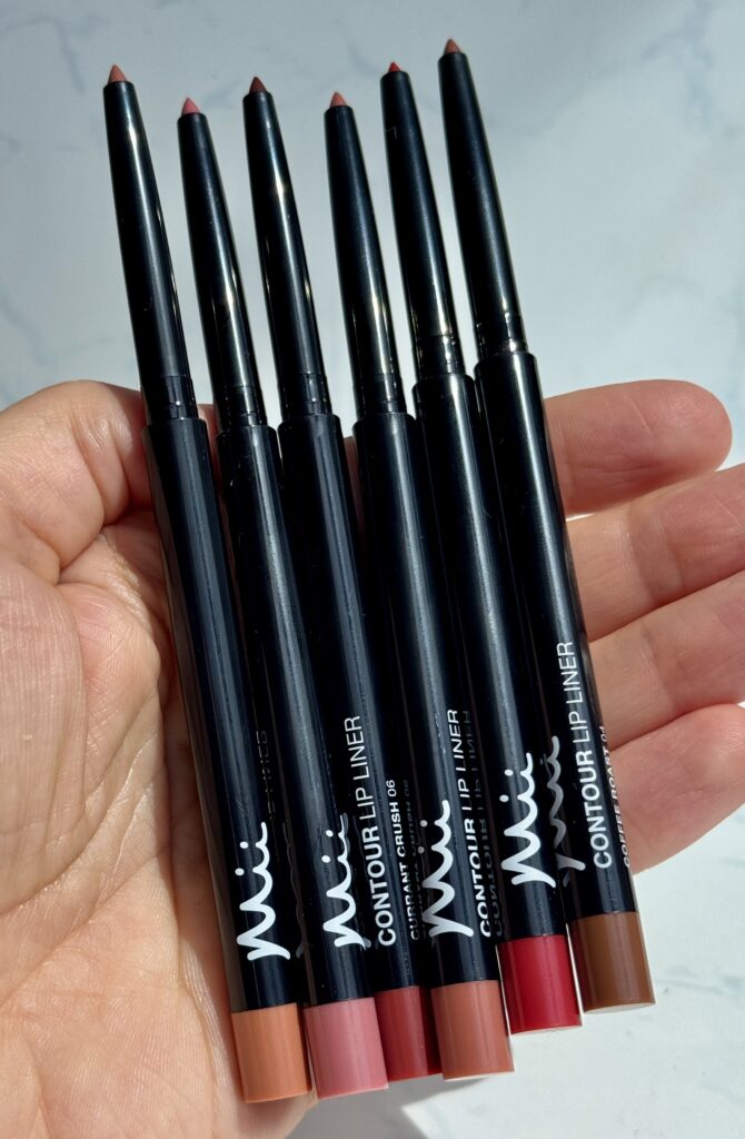 Hand holding all six shades of Mii Cosmetics Contour Lip Liner Pencils. Showing the fine pointed tip on all